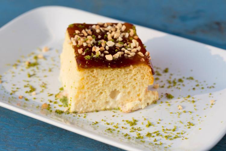 A plate with a piece of tres leches cake decorated with ground pistachio.