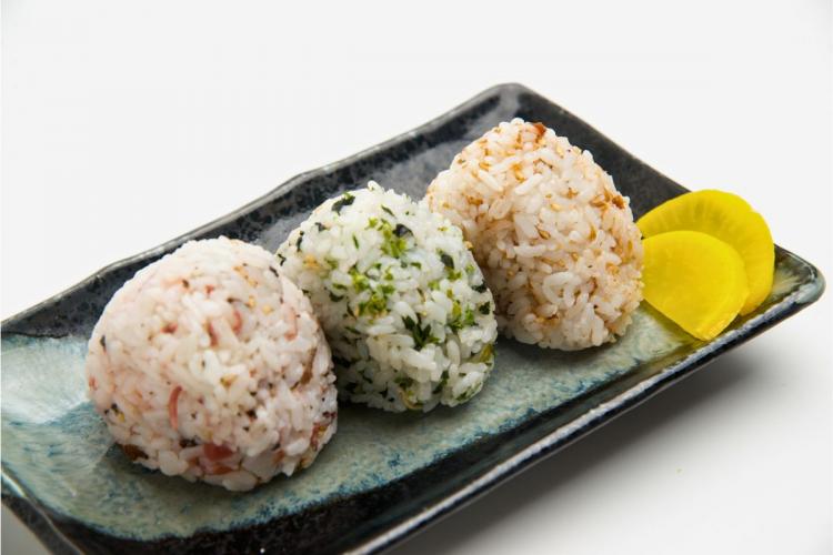 Three flavored onigiris with different flavors in a rectangular serving dish.