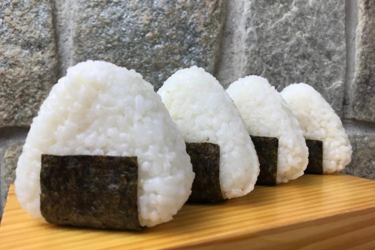 Four Japanese rice balls, known as onigiris, on a board.