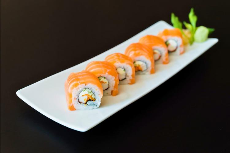 A rectangular serving dish with salmon sushi rolls.