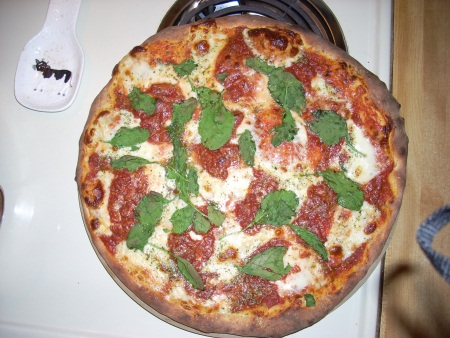 Pizza done with mozzarella and fresh basil.