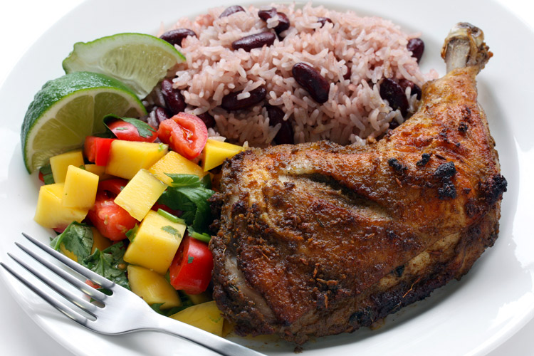 A plate with jerk chicken, rice and fresh fruit salsa.