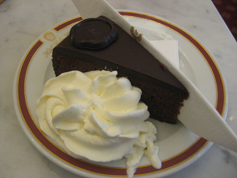A piece of sacher torte served with whipped cream.