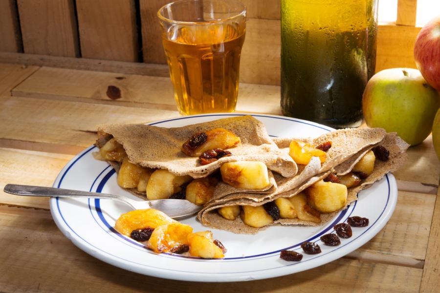 Apple stuffed crêpes with a glass and a bottle of cider.